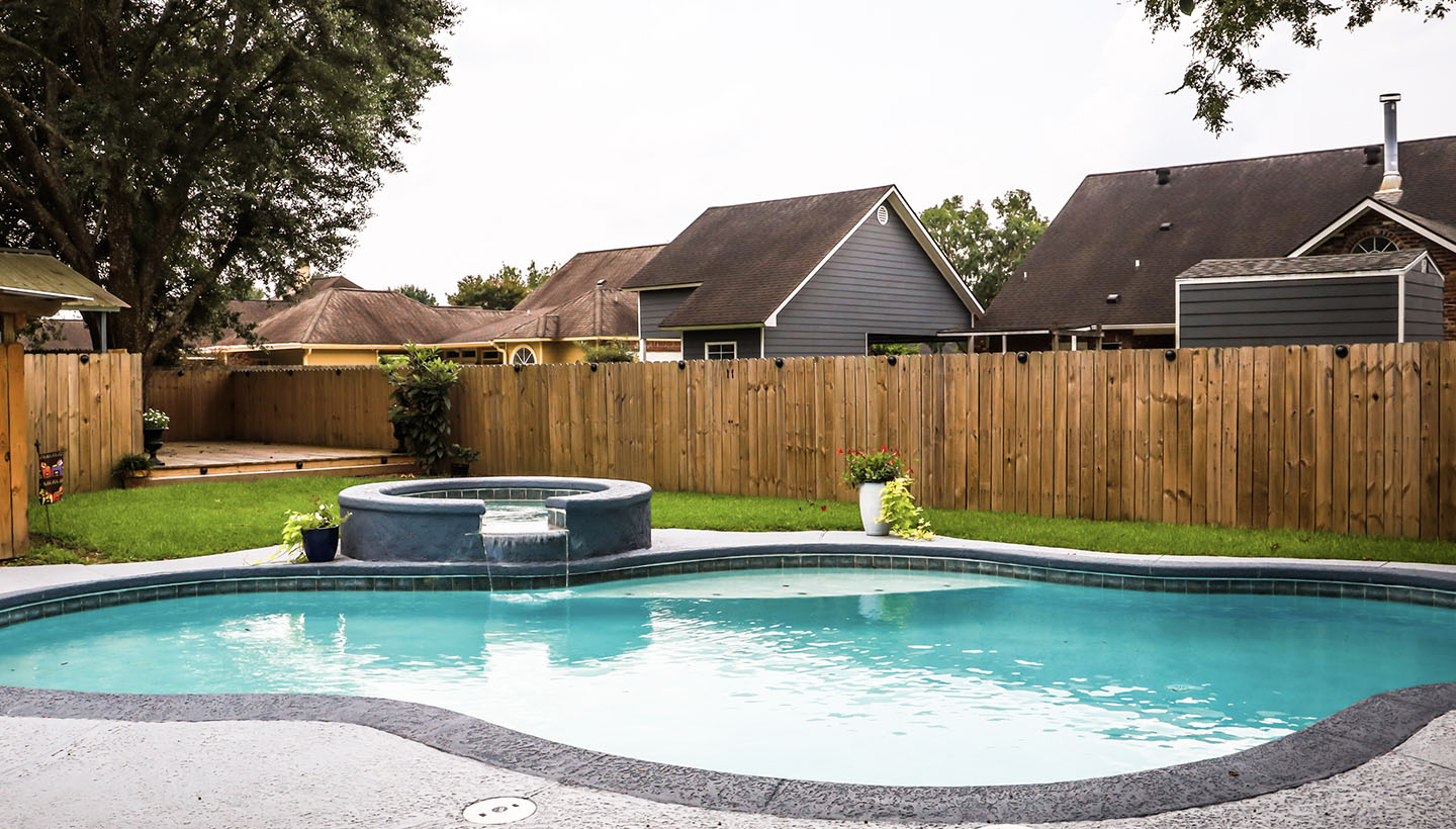 a residential swimming pool in a fenced in backyard